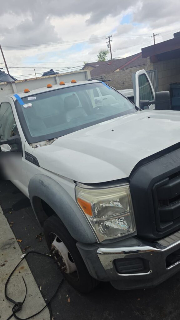 Ford F-450 work truck with a new windshield installed by Reyes Glass Group, tape holding it while the urethane cures