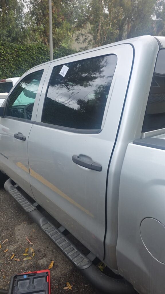 Silver Chevy Silverado crew cab with new rear door glass installed by Reyes Glass Group